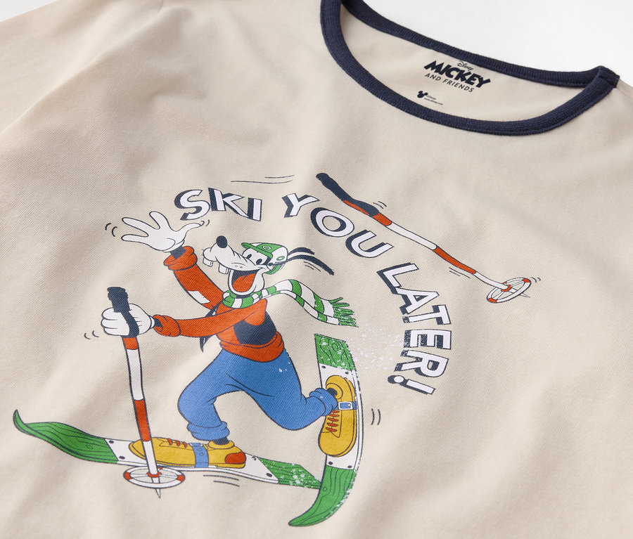 Detal bawełnianej koszulki z nadrukiem Goofy'ego na nartach i napisem "Ski you later!".