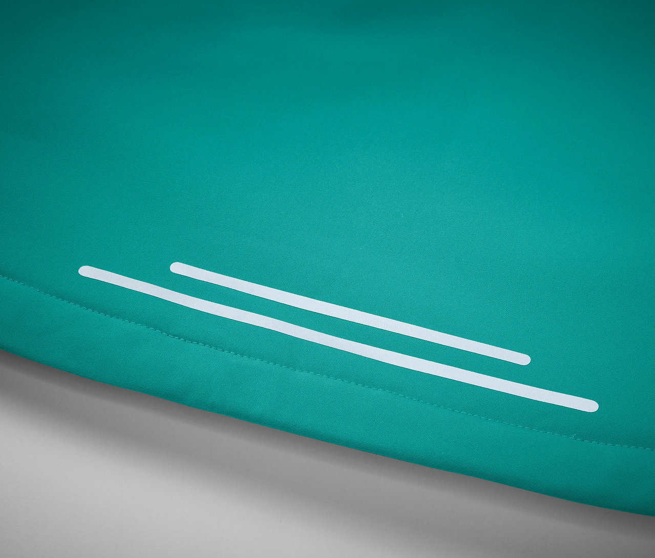 Szczegół turkusowego materiału z dwoma białymi paskami odblaskowymi.