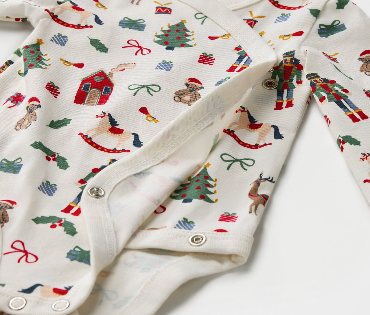 Zbliżenie bawełnianego body z świątecznym nadrukiem, zapinanego na zatrzaski.