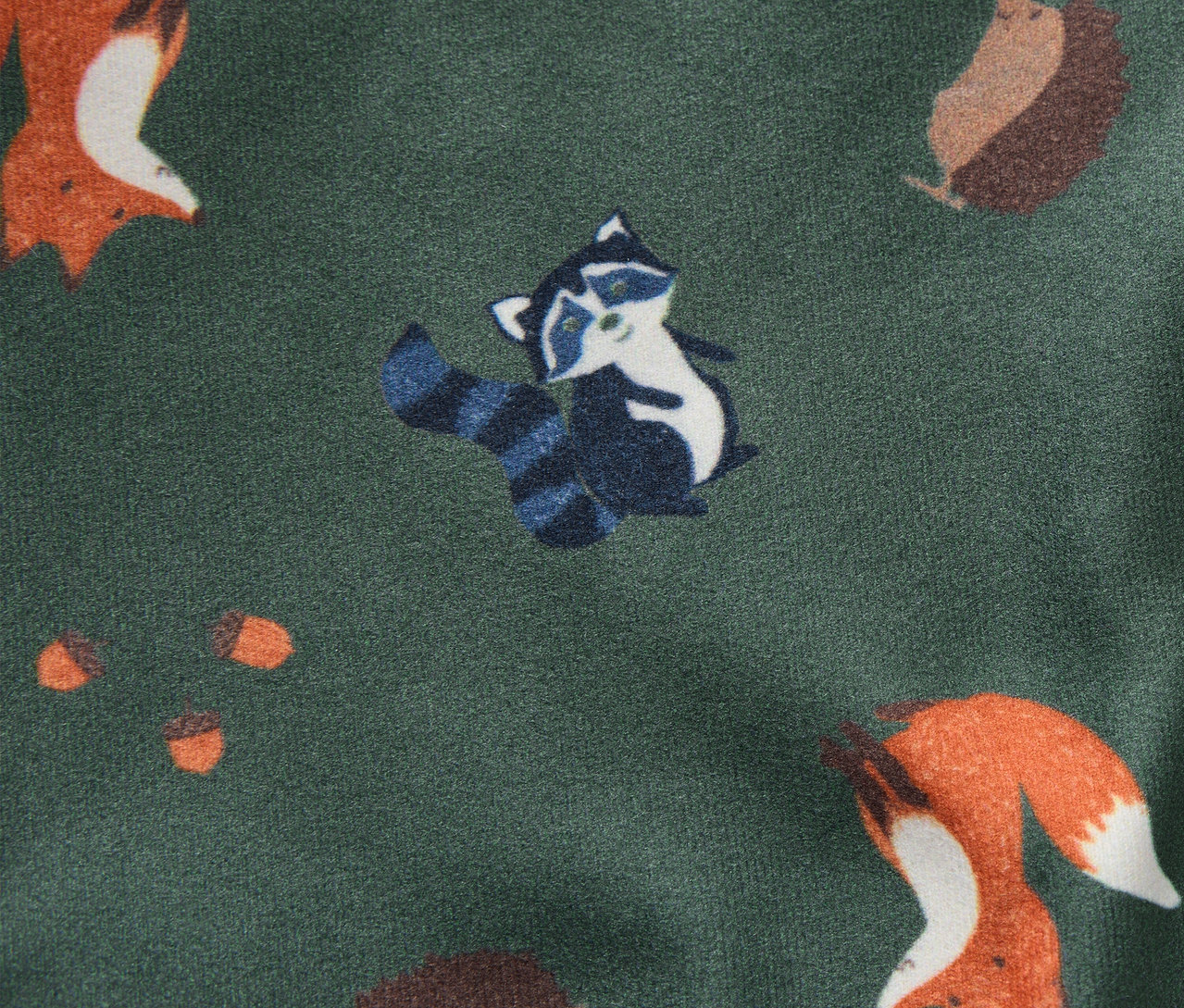 Wzór na dwustronnej kominiarce z lisami, szopami, jeżami i żołędziami na zielonym tle.