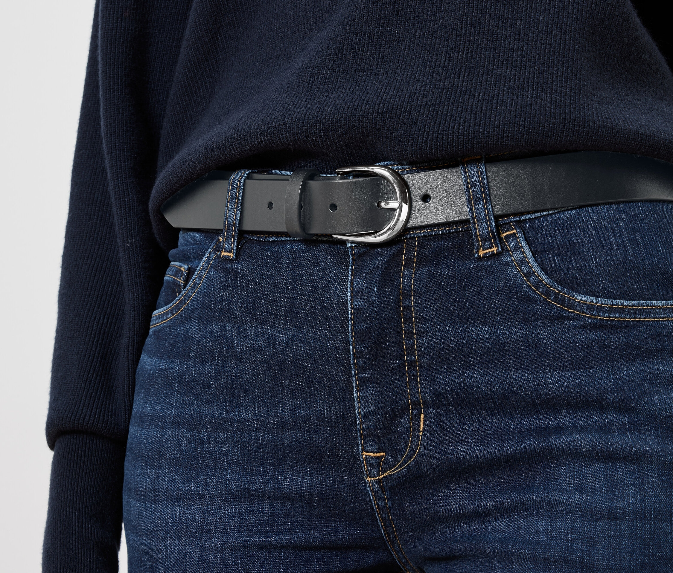 Czarny skórzany pasek na niebieskich dżinsach.