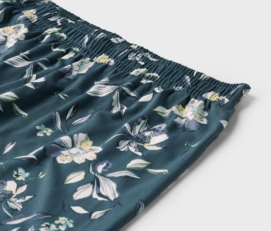 Szczegółowe ujęcie elastycznego pasa i kwiecistego wzoru spodni.