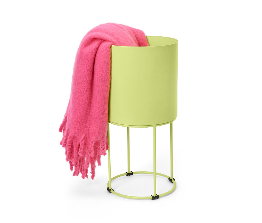 Różowy koc leży w okrągłej osłonie na doniczkę.