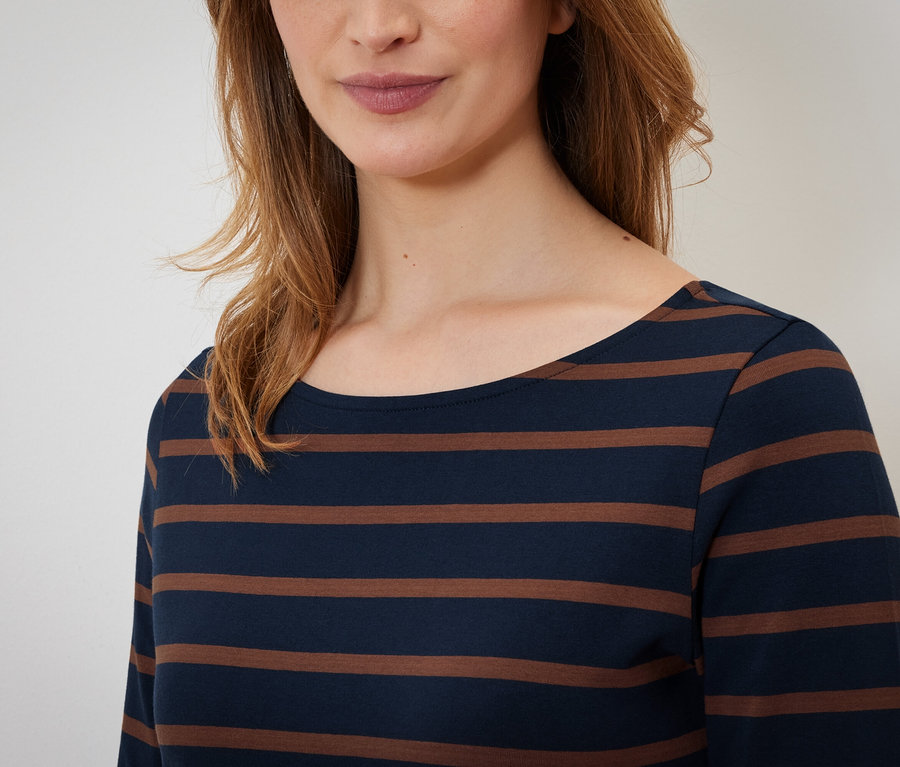 Górna część ciała kobiety w bluzce w paski z długim rękawem.