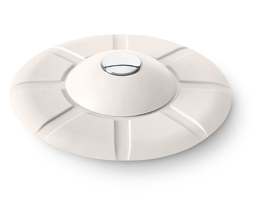 Kremowy, okrągły przedmiot z wypukłą górą i srebrnym guzikiem pośrodku.