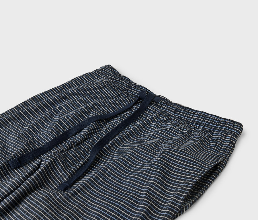 Zbliżenie na granatowe spodnie w kratę z elastycznym pasem i sznurkiem.