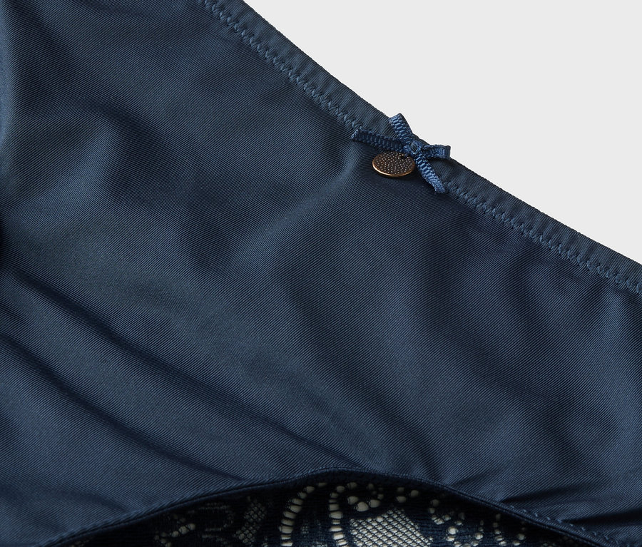 Szczegółowe ujęcie granatowych majtek z koronką i kokardką.