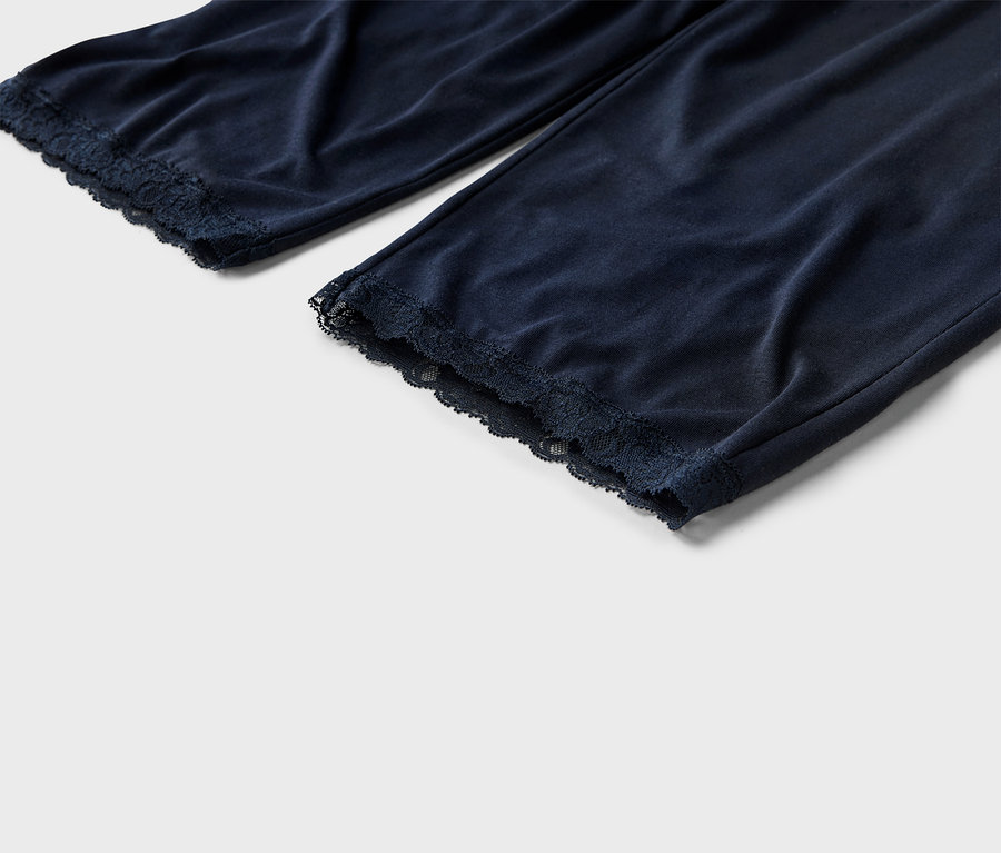 Zbliżenie na granatowe spodnie od piżamy z koronkowym obszyciem