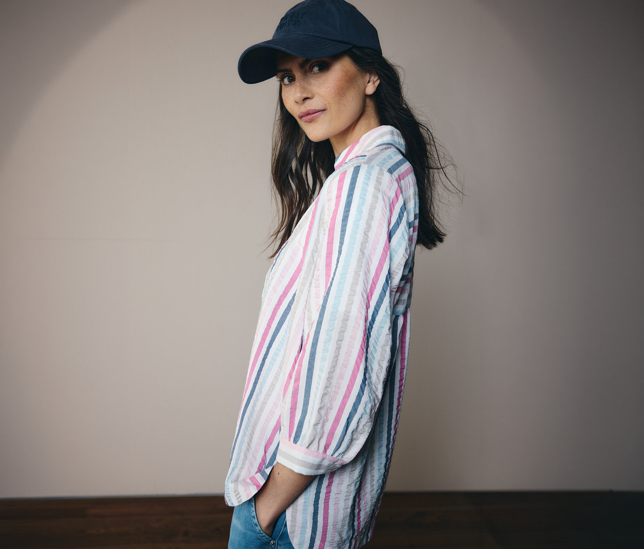 Kobieta w niebieskim kapeluszu i w paski bluzce koszulowej CECIL patrzy w kamerę.