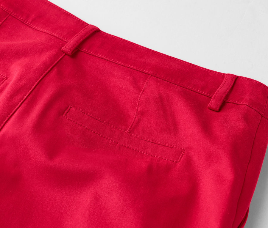 Szczegółowy widok tylnej części czerwonych spodni z kieszenią na pośladku i szlufkami na pasek.