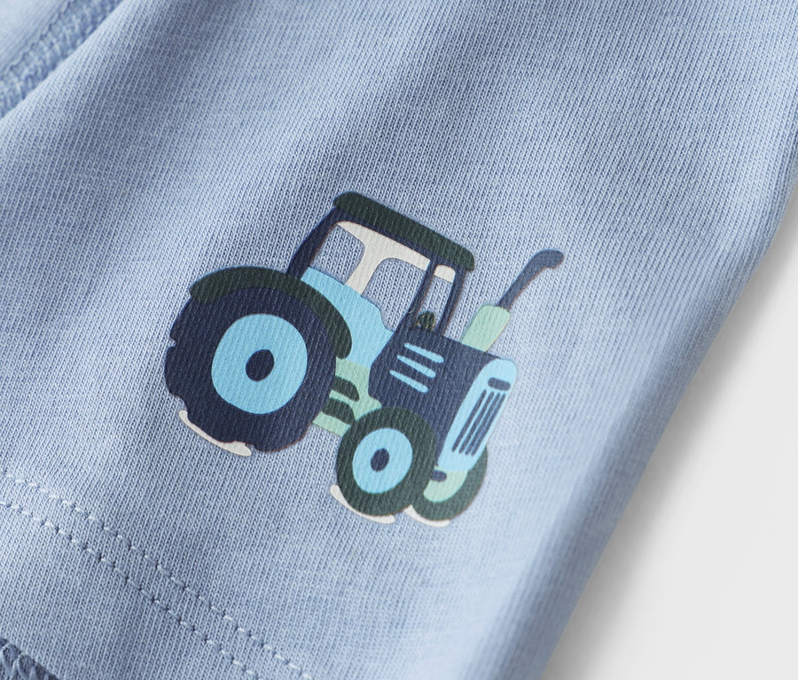 Szczegółowe ujęcie jasnoniebieskiego materiału z nadrukiem traktora.
