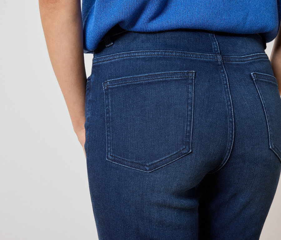 Zbliżenie na tył kobiety ubranej w ciemnoniebieskie dżinsy i niebieską bluzkę.