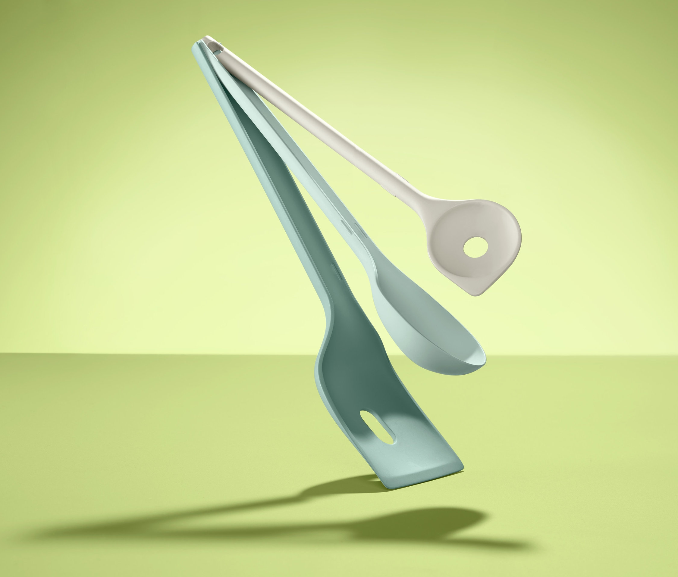 Lewitujące przybory kuchenne, 3 sztuki, na zielonym tle.