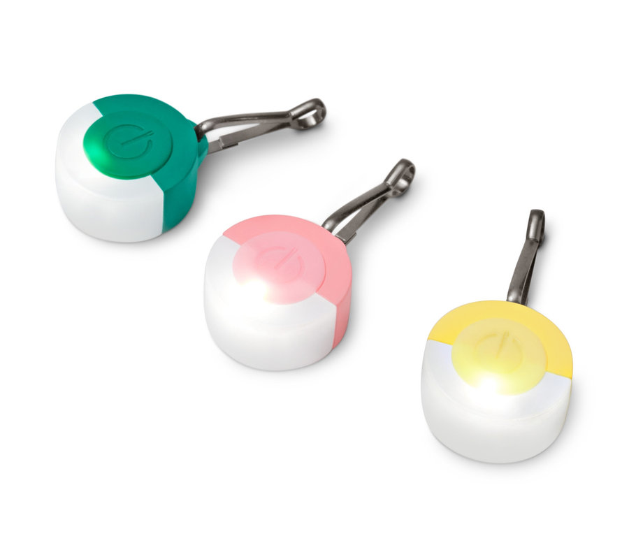 Trzy przywieszki odblaskowe LED leżą na białej powierzchni.