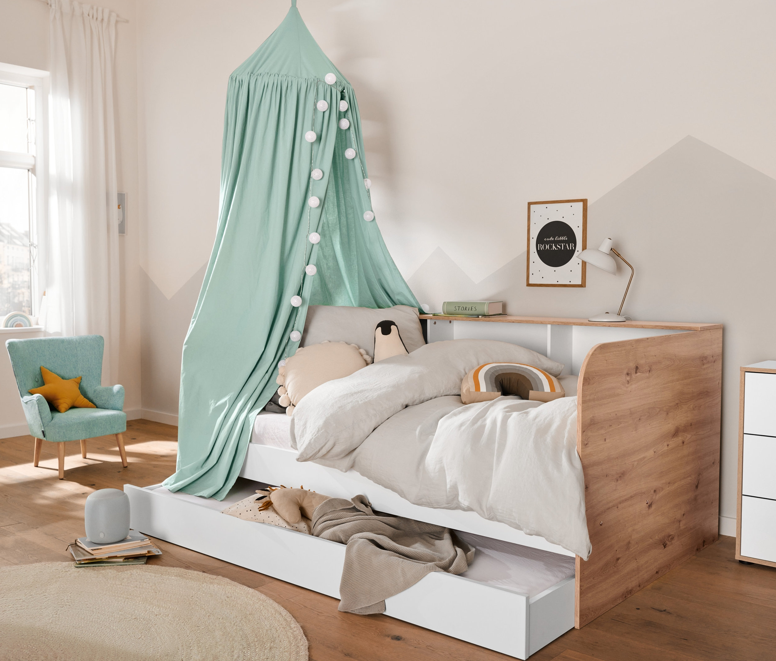 Pokój dziecięcy z łóżkiem ze skrzynią, komodą z krawędzią fornirowaną i szarym designerskim głośnikiem Bluetooth®.