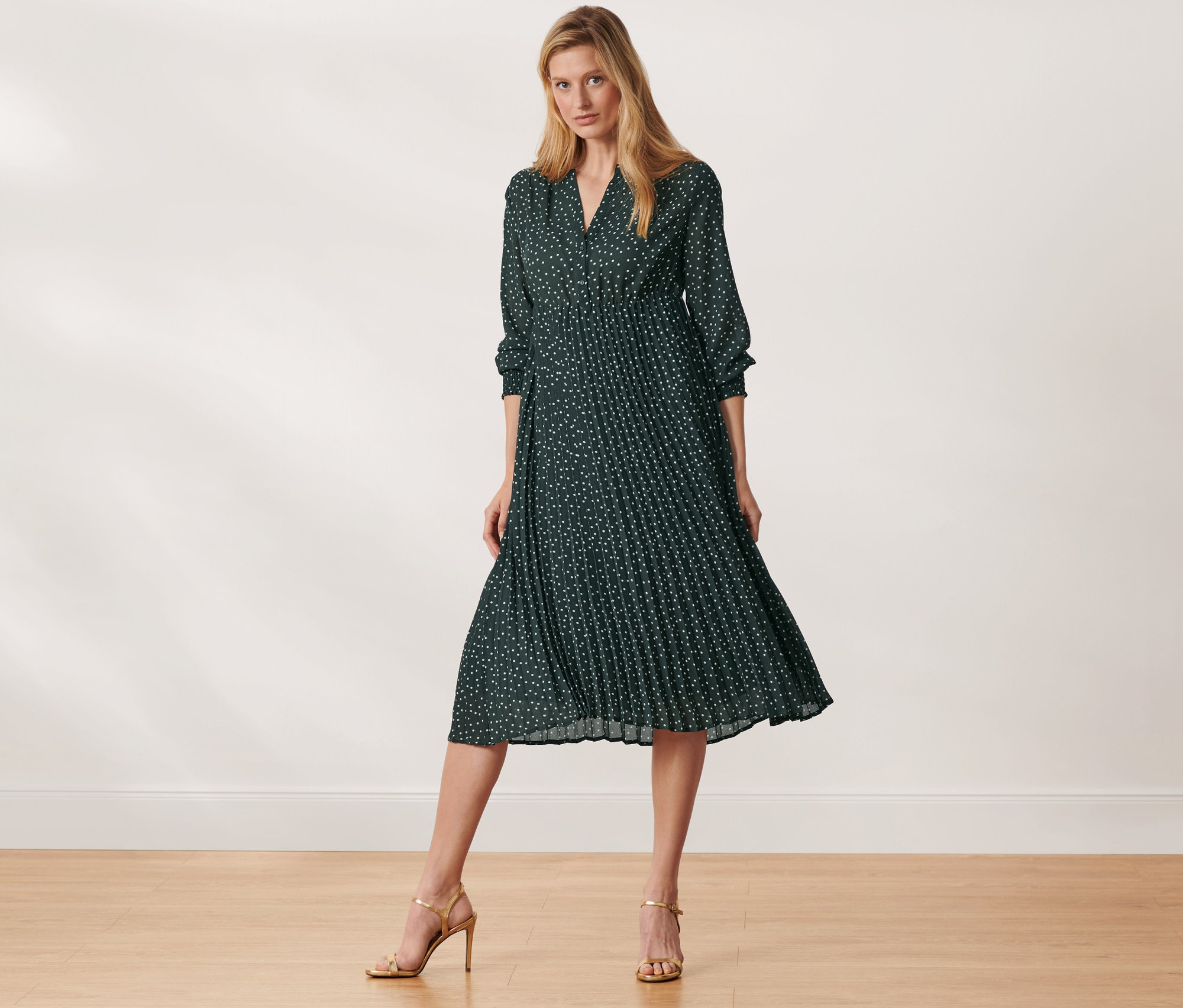 Kobieta pozuje w sukience midi w kropki.