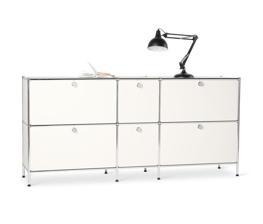 Metalowa szafka typu sideboard »CN3« duża, z 6 komorami z klapami, biała. Na górze leży otwarty notatnik i stoi czarna lampa.
