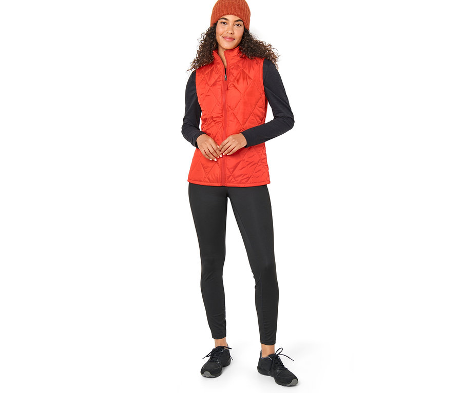 Kobieta ma na sobie pomarańczowy płaszcz przeciwdeszczowy 3 w 1 z kamizelką i brązową czapkę.