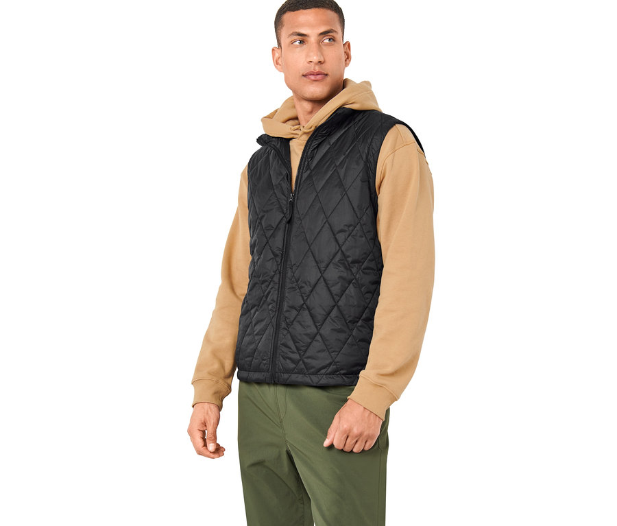 Mężczyzna ma na sobie czarną kamizelkę z kurtki outdoorowej 3 w 1 i oliwkowozielone spodnie.