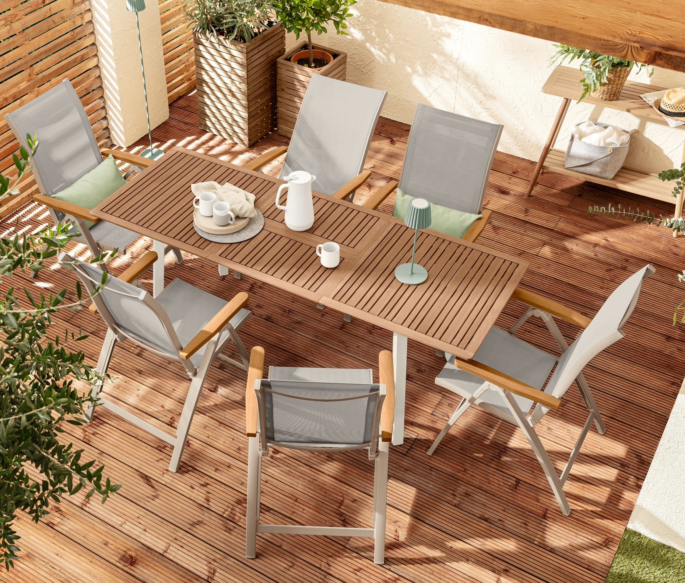 Widok z góry na zestaw mebli ogrodowych z sześcioma krzesłami »Liska«, stołem rozkładanym »Liska«, dwoma lampami stołowymi LED, dwoma donicami »Tinus« i konsolą.