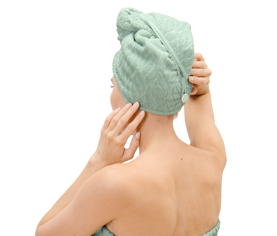 Kobieta poprawia ręcznik-turban na głowie.