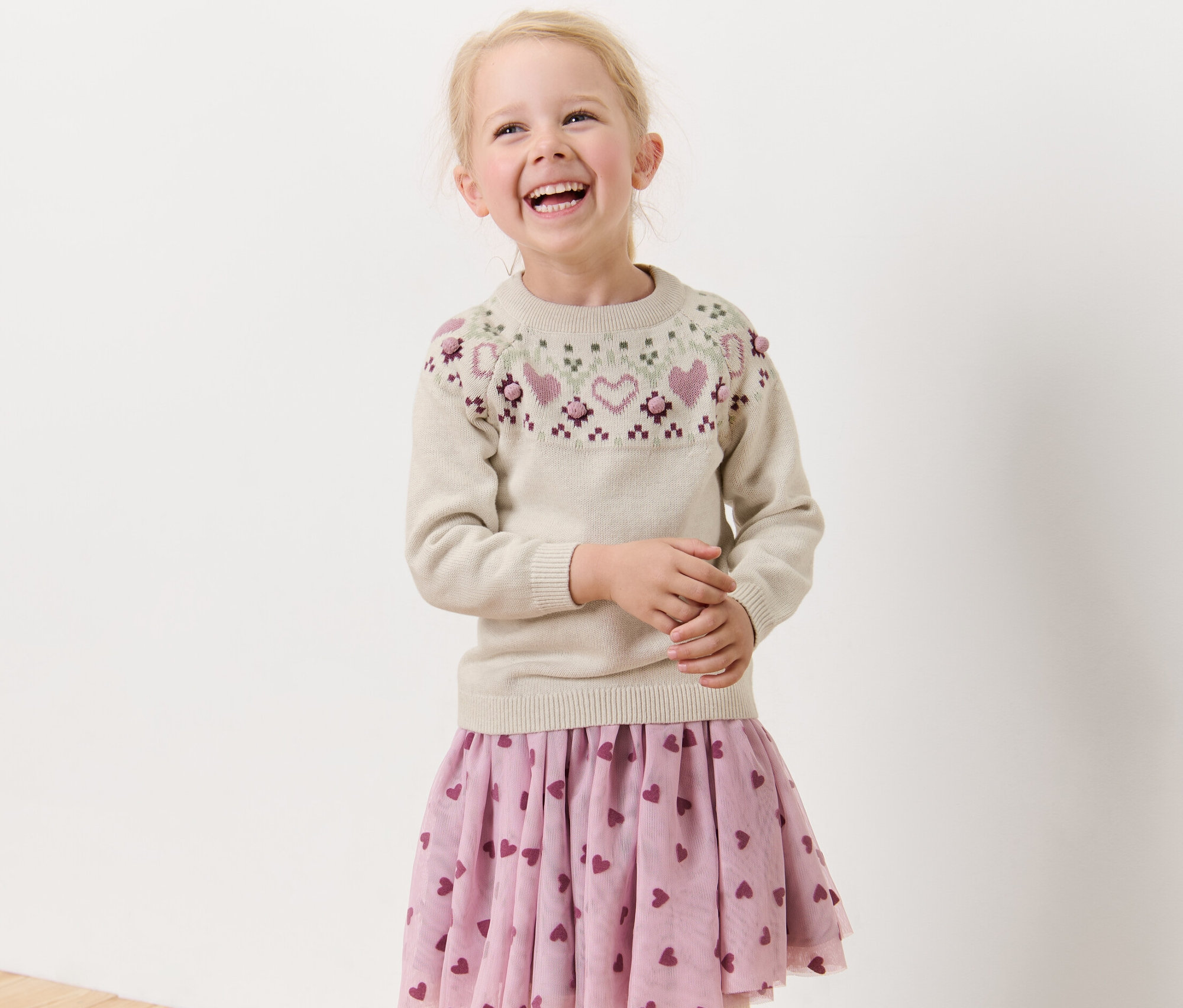 Uśmiechnięta blondynka ma na sobie sweter.