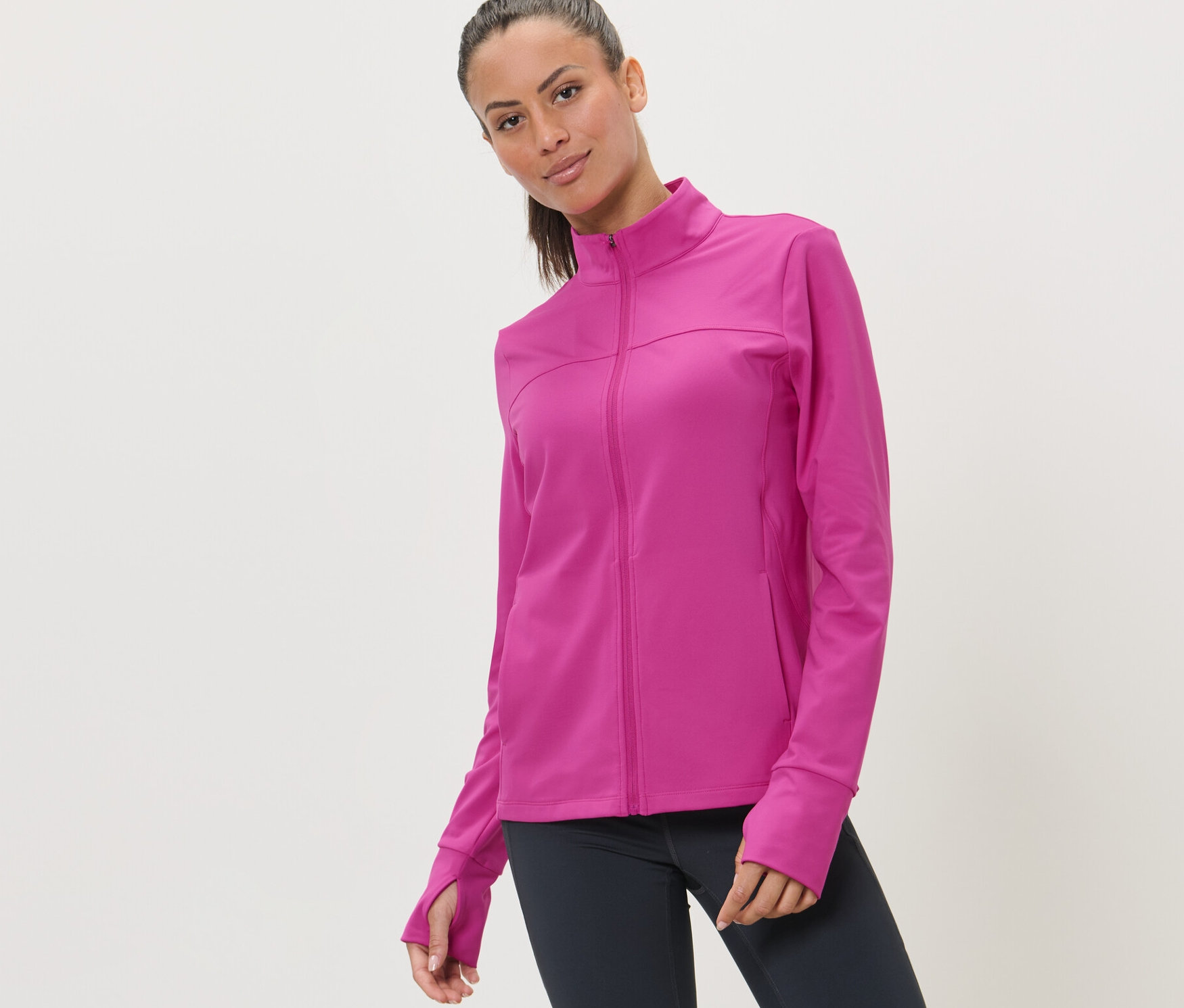 Kobieta ma na sobie różową rozpinaną bluzę sportową.