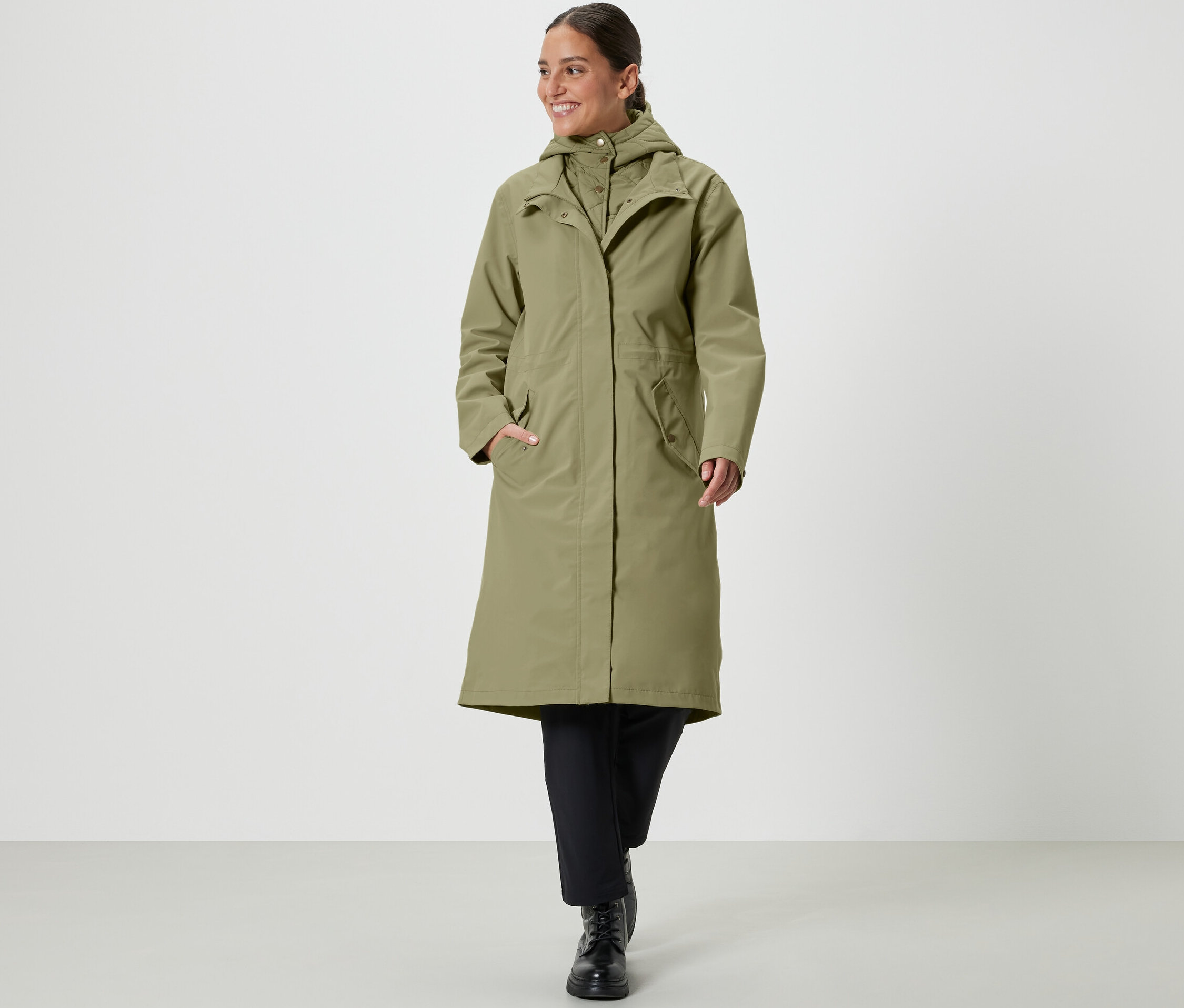 Kobieta idzie i ma na sobie płaszcz przeciwdeszczowy w kolorze khaki.