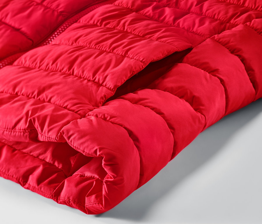 Zbliżenie na czerwoną kamizelkę pikowaną z kapturem i kieszenią.