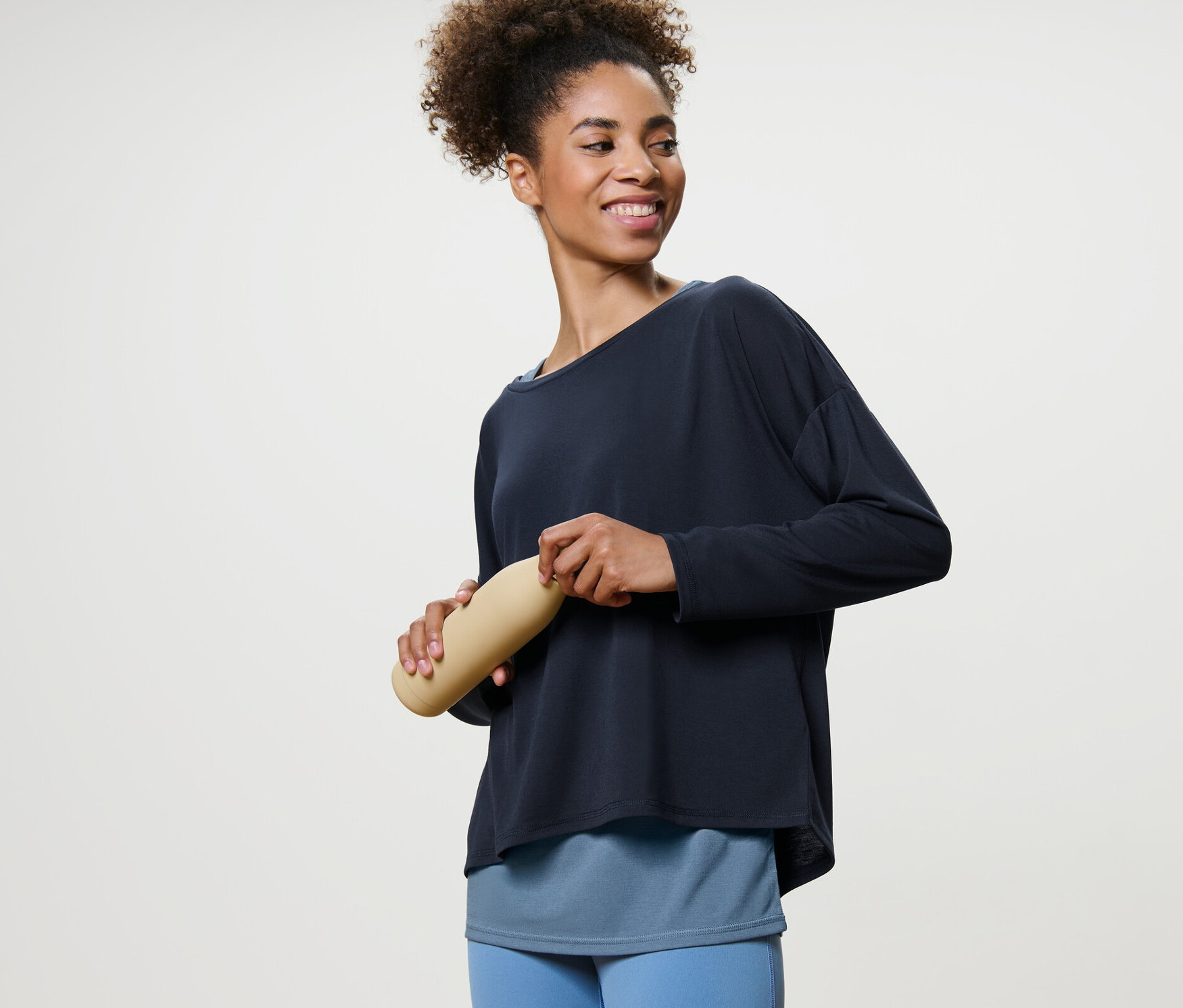 Kobieta trzyma butelkę z wodą i ma na sobie niebieską koszulkę sportową 2 w 1.