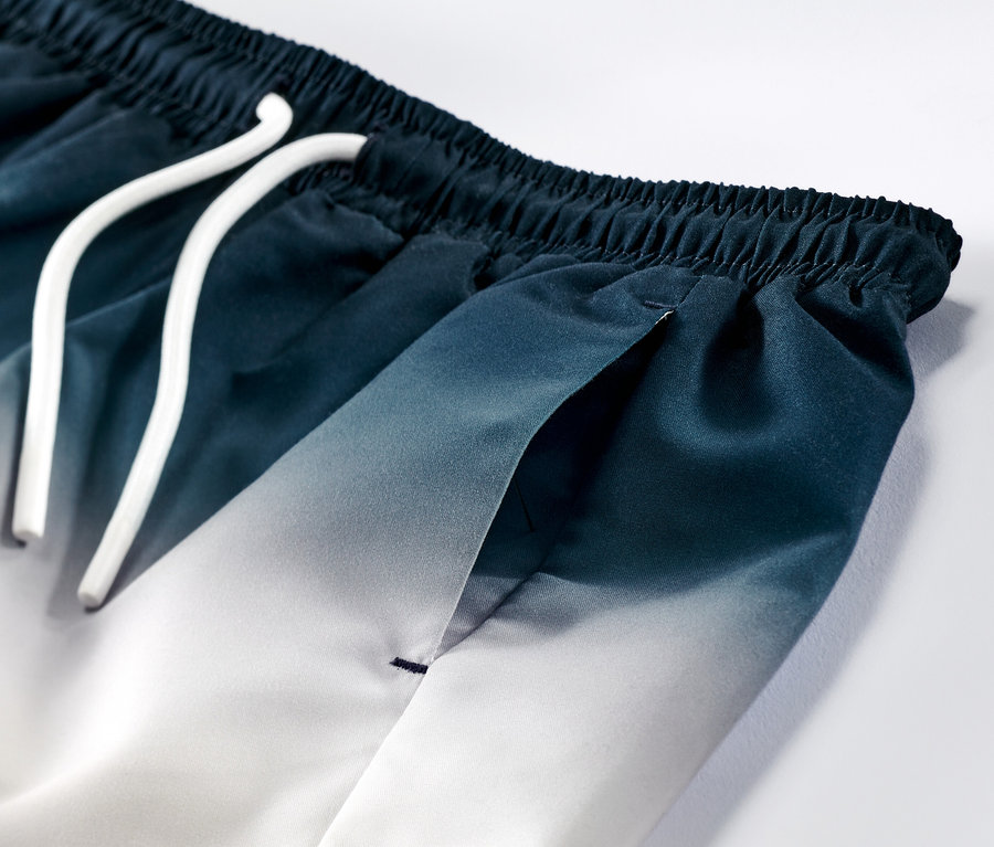 Zbliżenie na szorty do pływania z gradientem koloru niebiesko-białego i białym sznurkiem.