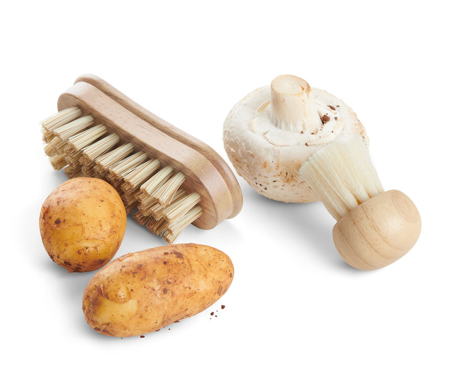 Dwa ziemniaki i pieczarka obok dwóch szczoteczek do czyszczenia warzyw.