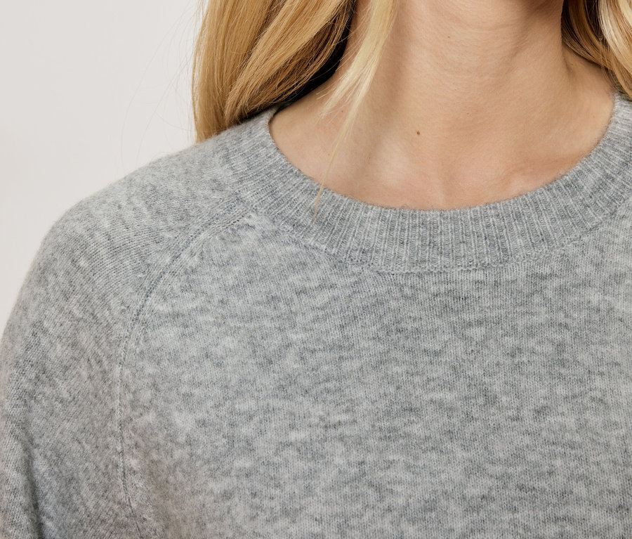 Zbliżenie na damski szary sweter z okrągłym dekoltem.