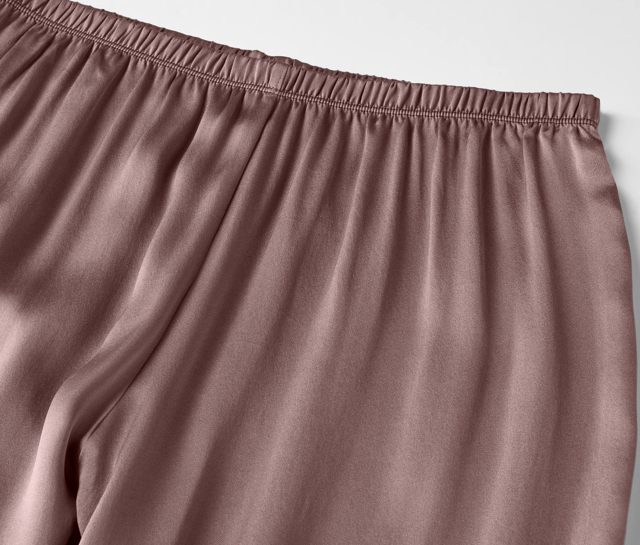 Zbliżenie liliowych satynowych spodni od piżamy z elastycznym pasem.
