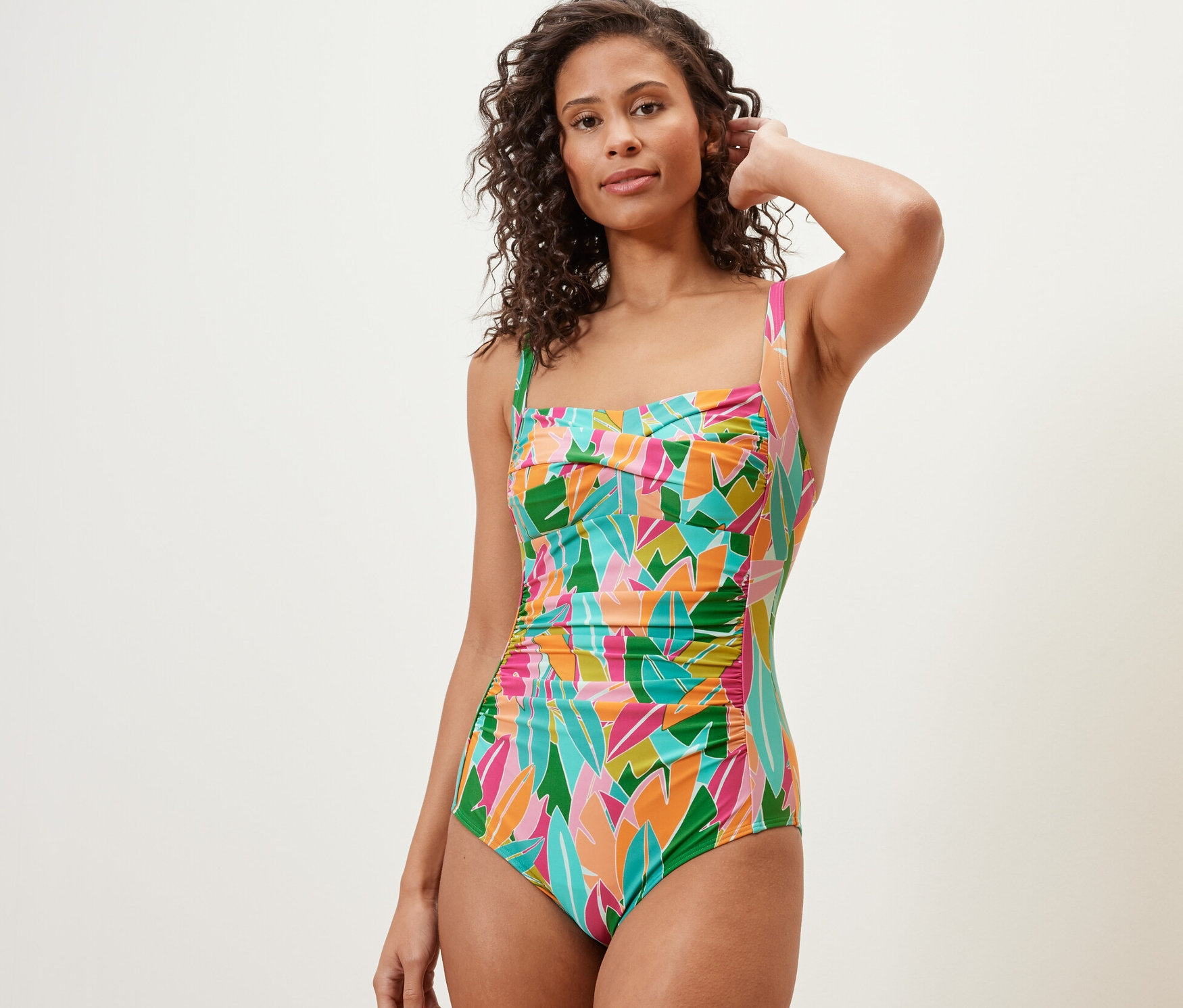 Kobieta pozuje w wielokolorowym, modelującym kostiumie kąpielowym.