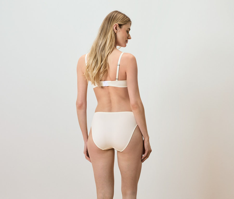Widok z tyłu na kobietę z blond włosami w beżowym biustonoszu i majtkach.