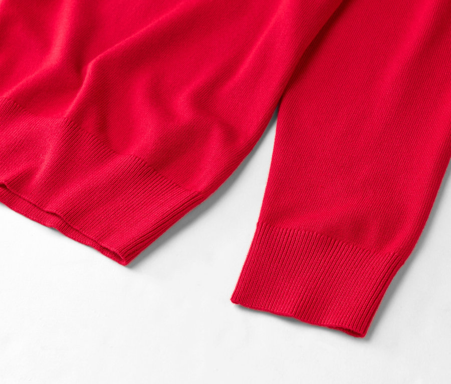 Szczegółowy widok czerwonego swetra na białym tle.