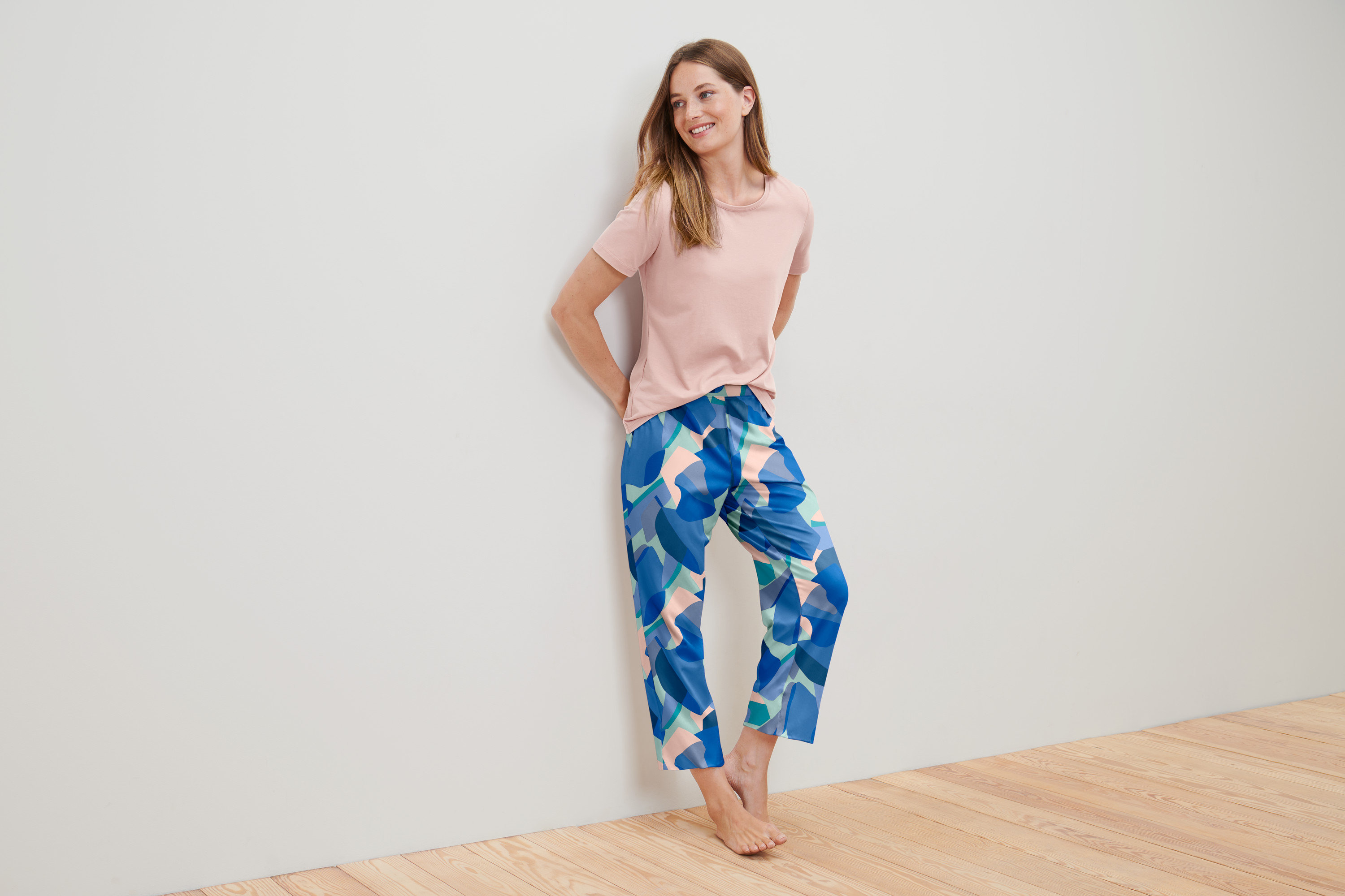 Kobieta opiera się o ścianę w piżamie.