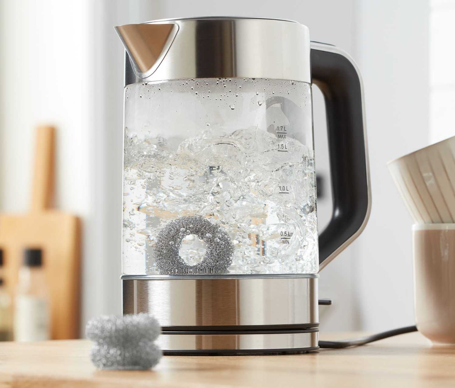 Czajnik z gotującą się wodą i 2 sztukami odkamieniaczy.