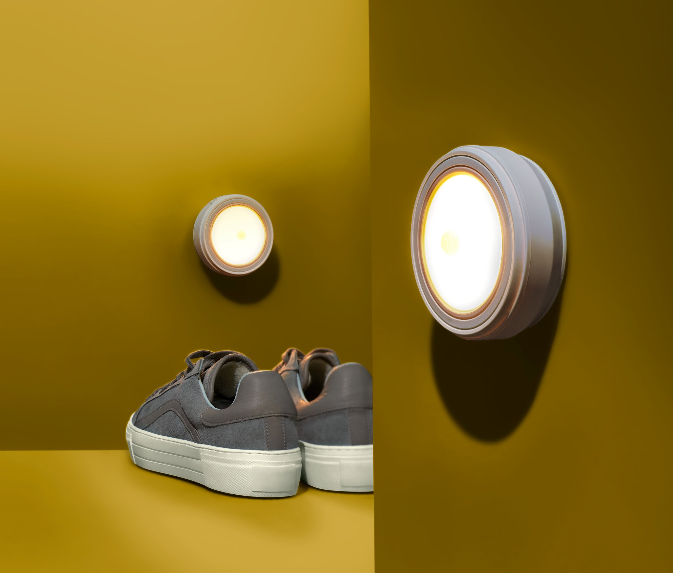 Dwie lampki LED na żółtej ścianie, pod nimi buty.