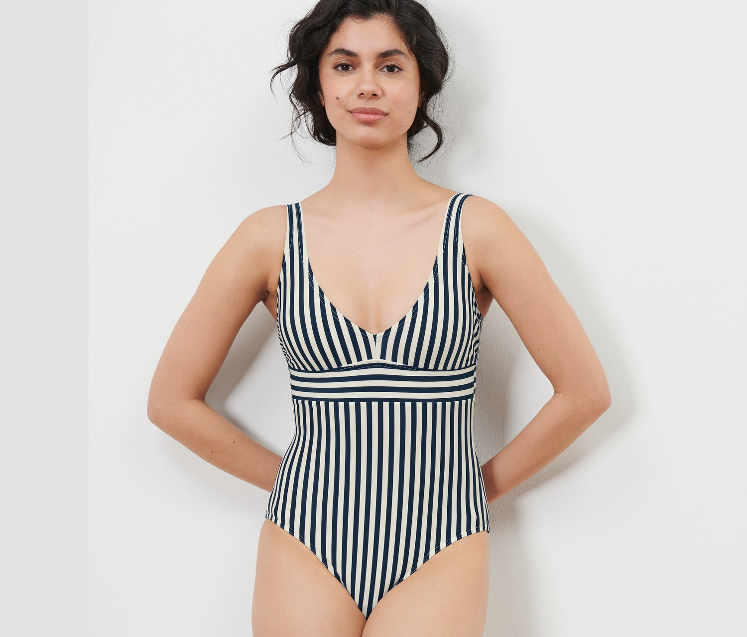 Kobieta pozuje w kostiumie kąpielowym w niebiesko-białe paski.