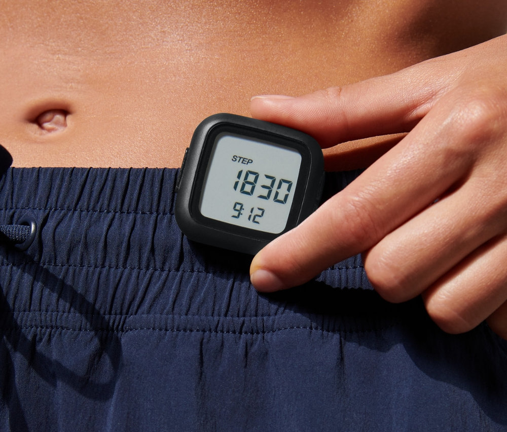 Kobieta trzyma w ręku krokomierz.