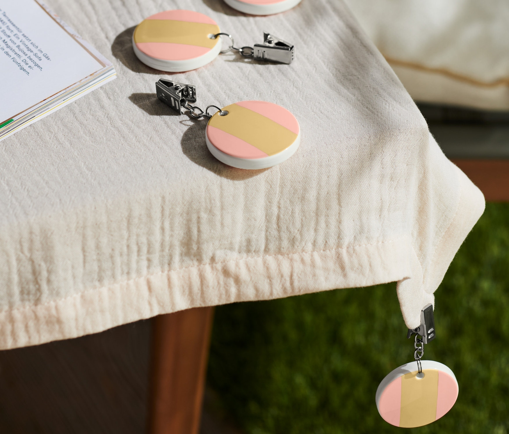 Na stole leżą filiżanka kawy i 4 ciężarki do obrusu.