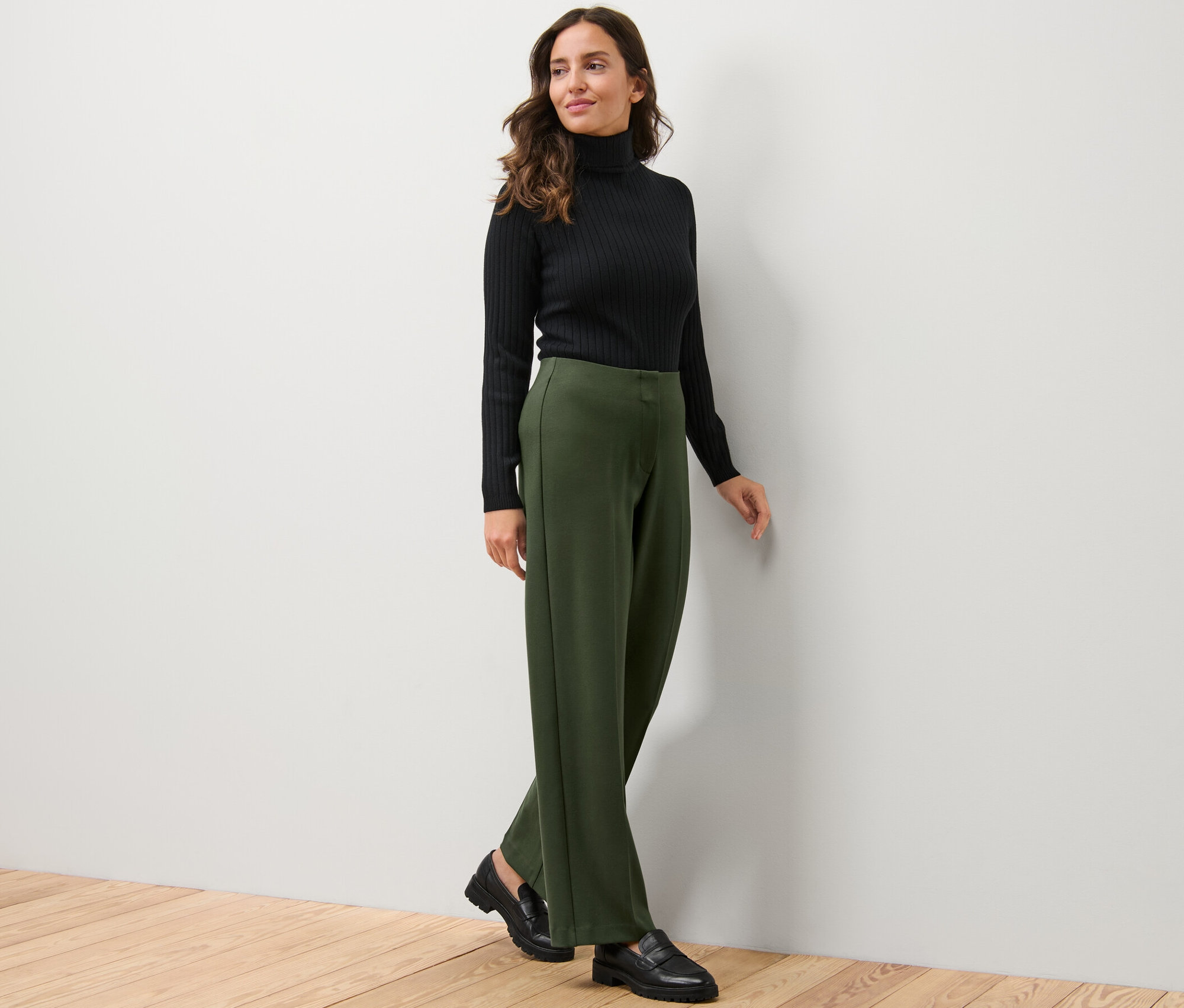 Kobieta w czarnym golfie i spodniach dżersejowych.