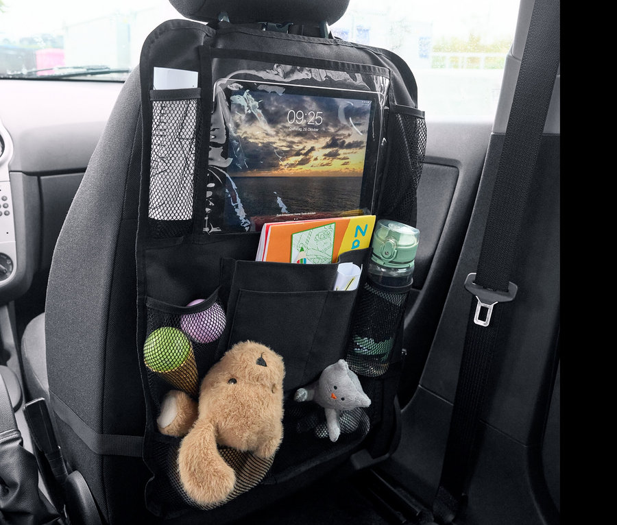 Czarny organizer na oparcie fotela z zabawkami, książkami i tabletem.