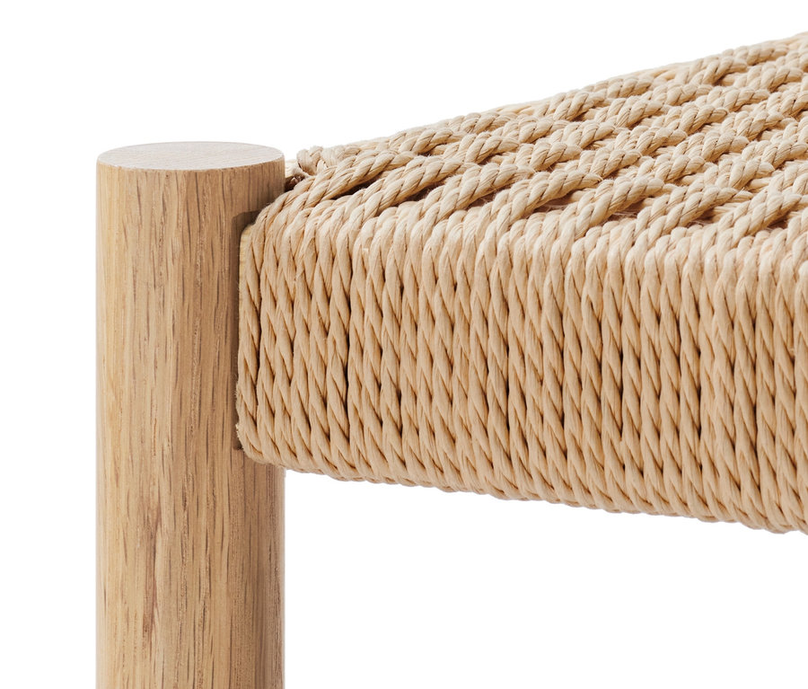 Detal drewnianej ławki z plecionym siedziskiem.