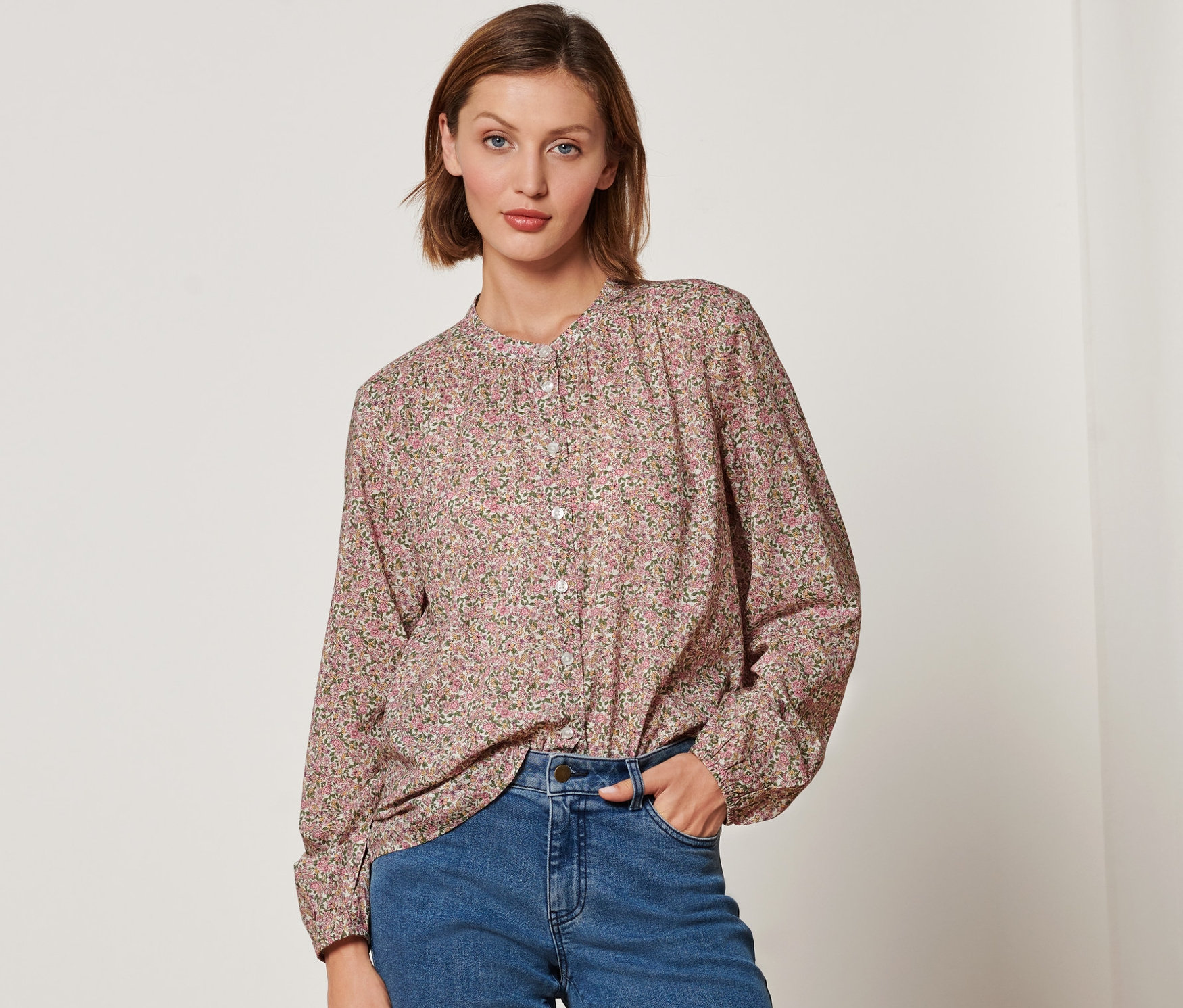 Kobieta ma na sobie bluzkę w kwiecisty wzór i dżinsy.