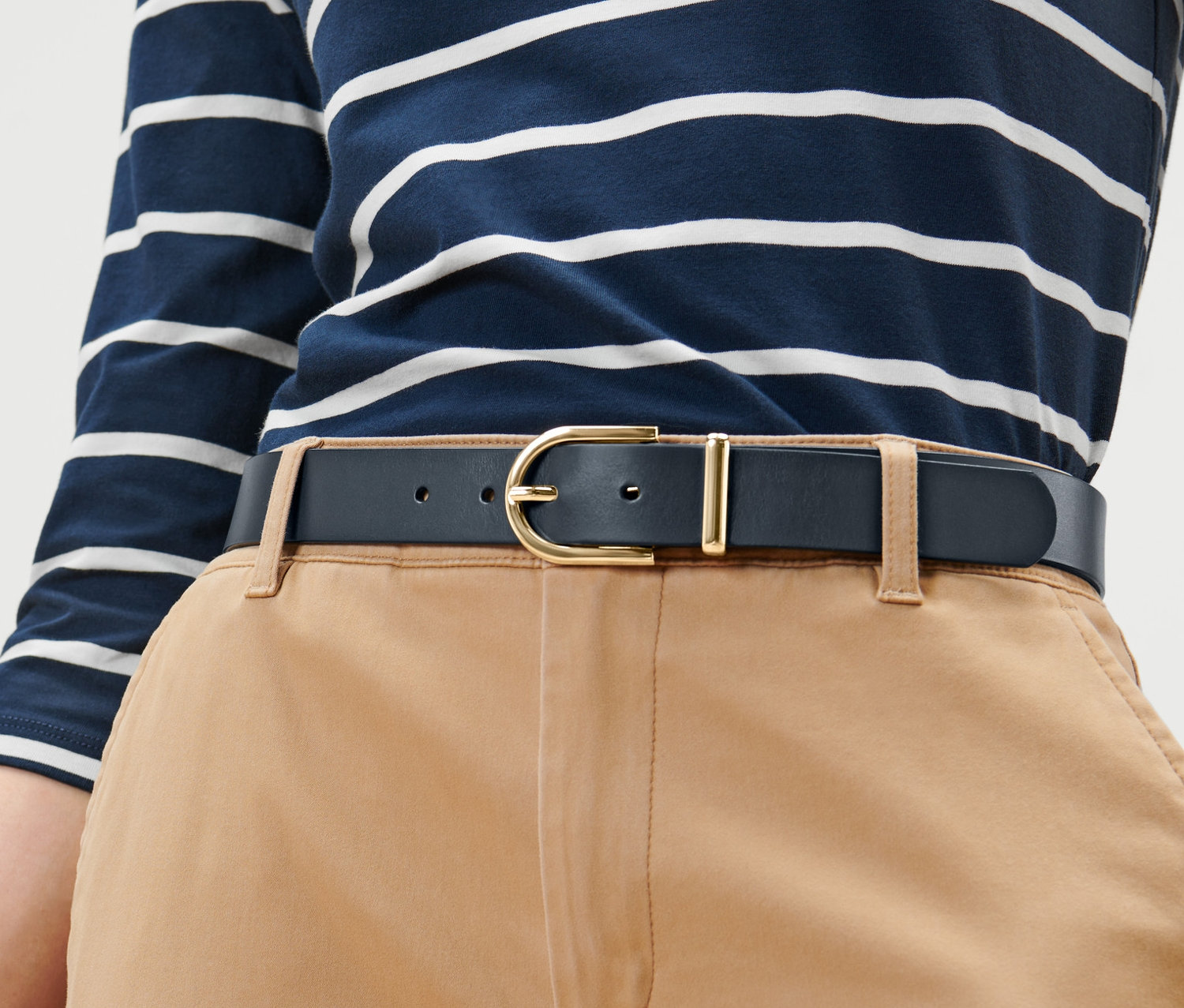 Kobieta ma na sobie skórzany pasek z metalową klamrą.