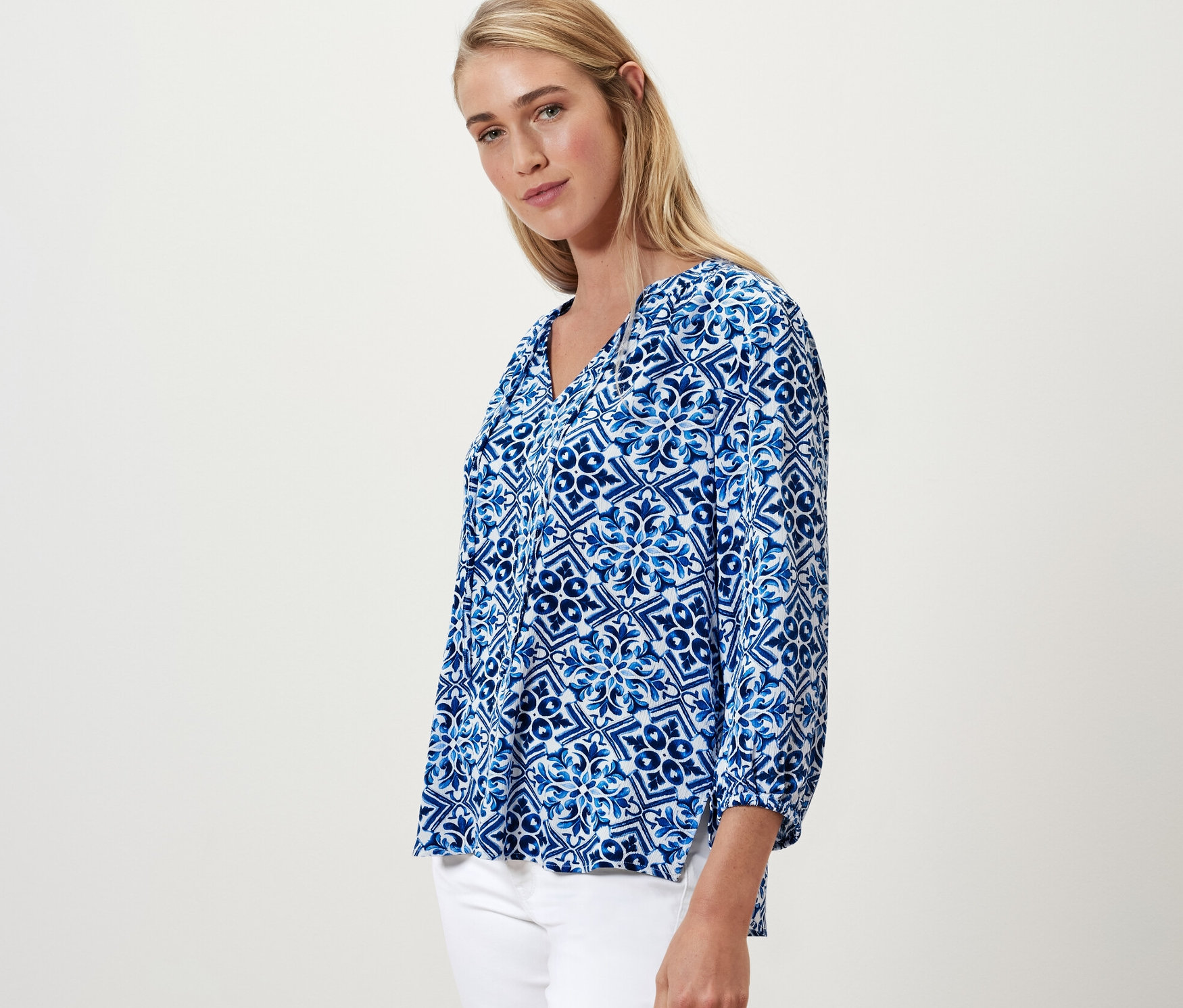 Blondynka pozuje w niebieskiej bluzce-tunice z nadrukiem.