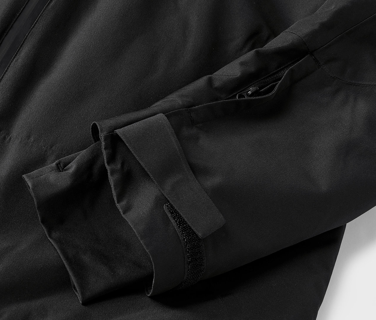 Szczegół czarnej kurtki z rękawem i zamkiem błyskawicznym.